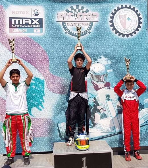 Karl Saad standing first on the podium with a trophy